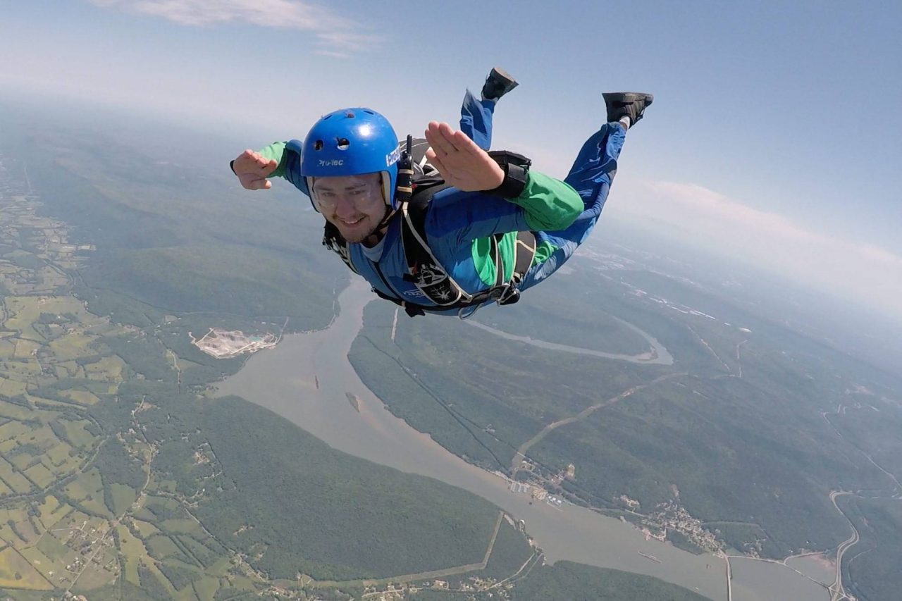 Man in green skydiving gear smiles during AFF training at the Skydive Company