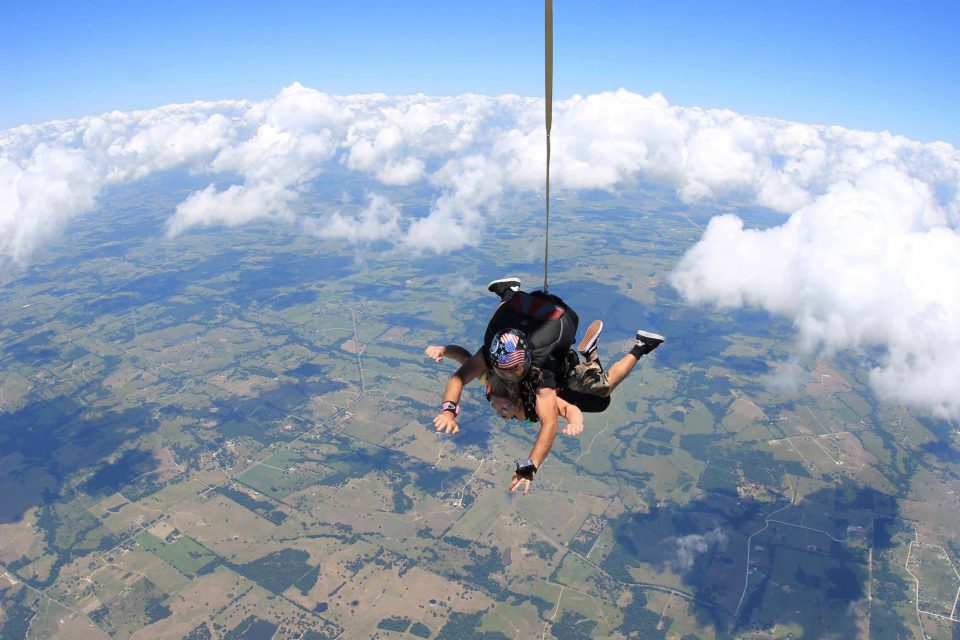 Tandem instructor with an American flag on his helmet enjoys a beautiful skydive