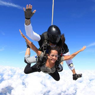Women in camo shirt smiles during free fall portion of her skydive