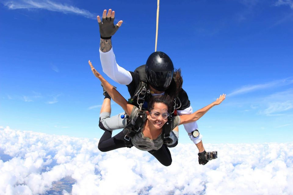 Women in camo shirt smiles during free fall portion of her skydive