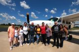 Family members gather around with tandem skydivers in front of the skydiving company aircraft