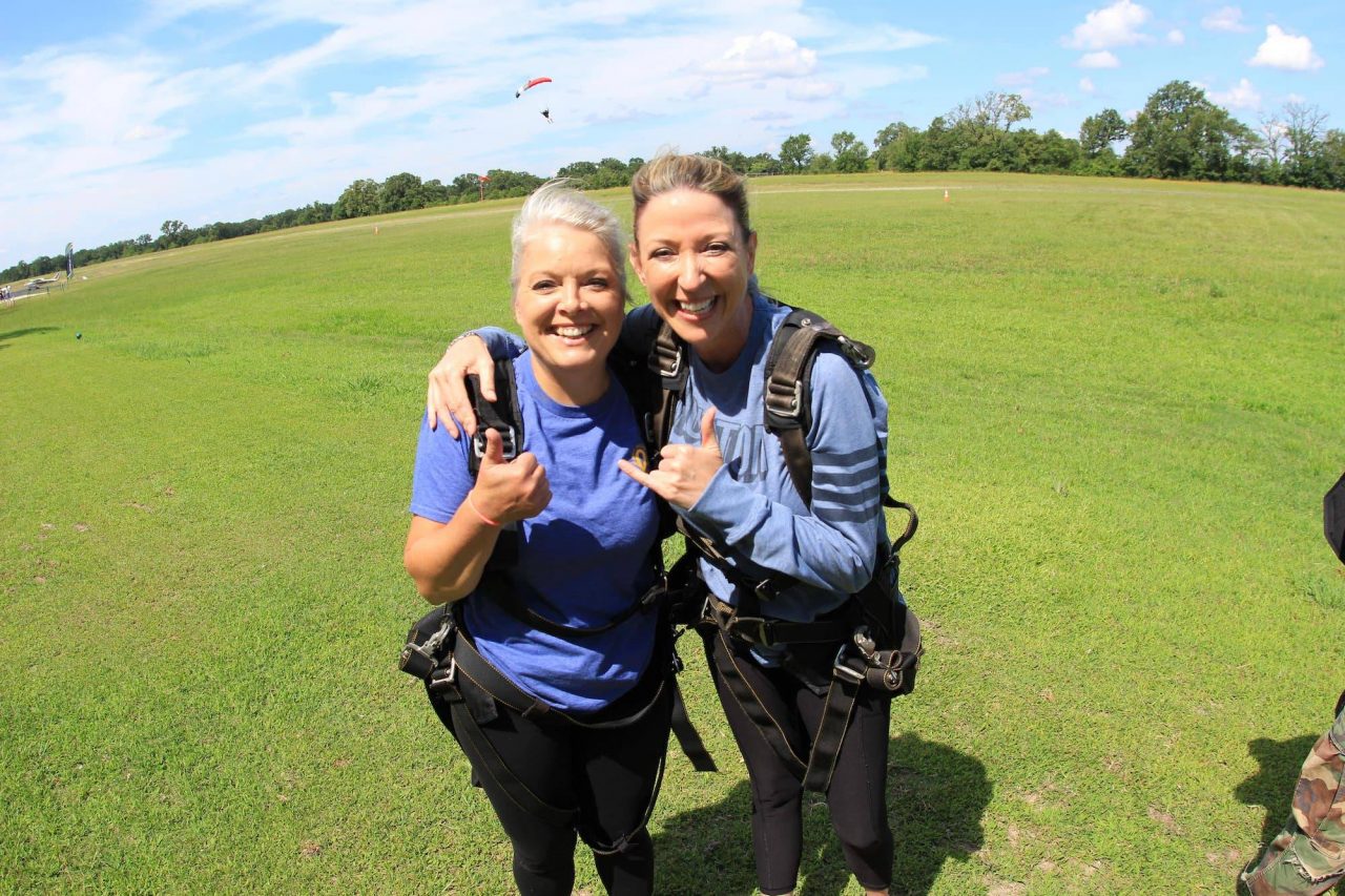 Two women celebrate on the ground after an awesome skydive at the skydiving company