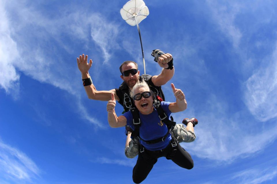 Women in blue shirt gives two thumps up during an awesome skydive at the skydiving company