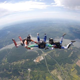 AFF student practicing flying positions during his skydive with two instructors at the skydiving company