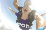 College student wearing a purple shirt enjoys her skydive at the skydiving company in texas